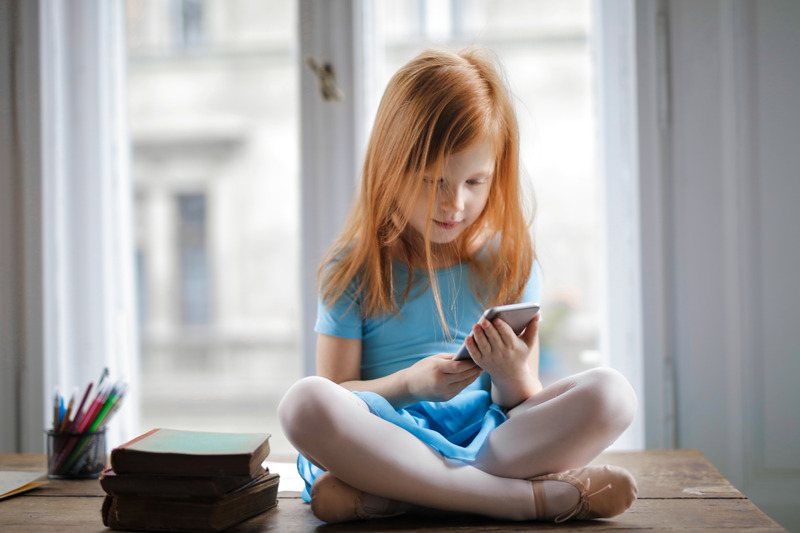 Girl learning on phone while mom works at home with kids